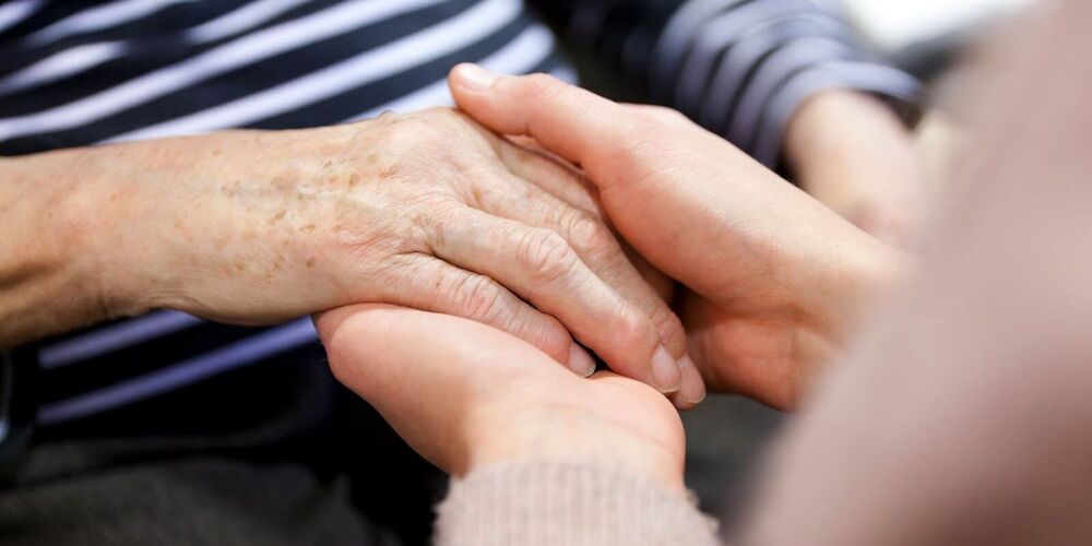 Zwei Hände, die eine andere Hand behutsam halten. 