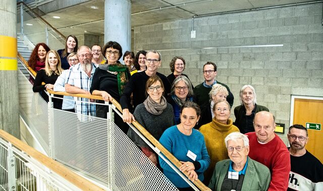 Ein Team von Mitarbeitern steht auf einer Treppe für ein Gruppenbild.