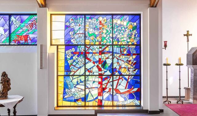Glasfenster in einer Kapelle, welches mit unterschiedlich farbigen Scheiben bestückt ist. 