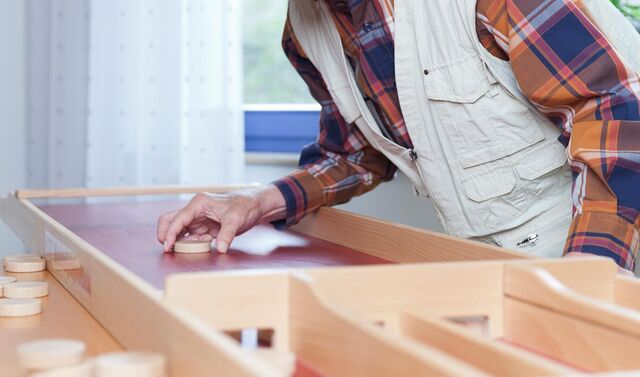 Ein älterer Mann beugt sich über ein Shuffelboard und hält einen Spielstein in der Hand. 