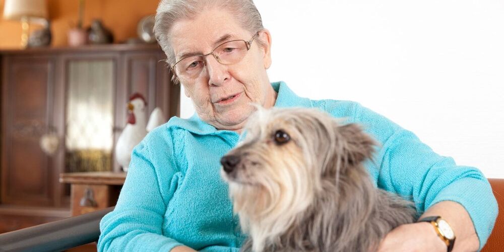 Eine Bewohnerin des Seniorenhauses Haus Maria Hilf mit einem Hund. Die Seniorin hat beide Arme um diesen gelegt. 