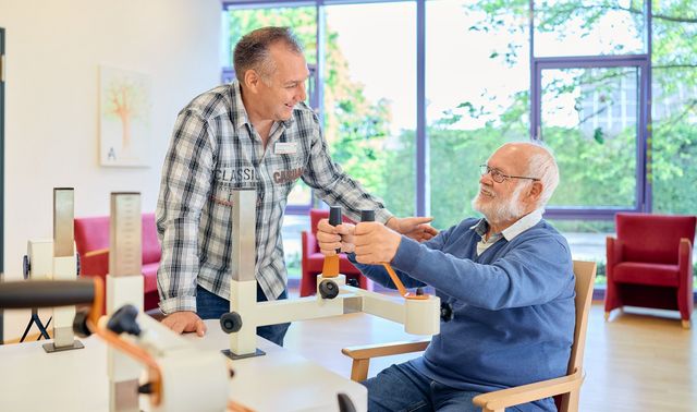 Dirk Kossiak, Leiter der Tagespflege Viersen, lächelt einen Senior an.